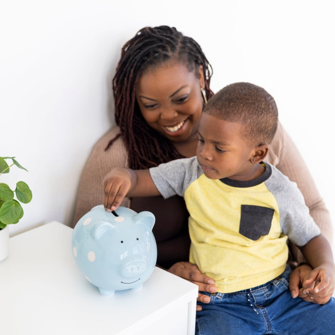 small child and his mother putting coins into the blue piggy bank