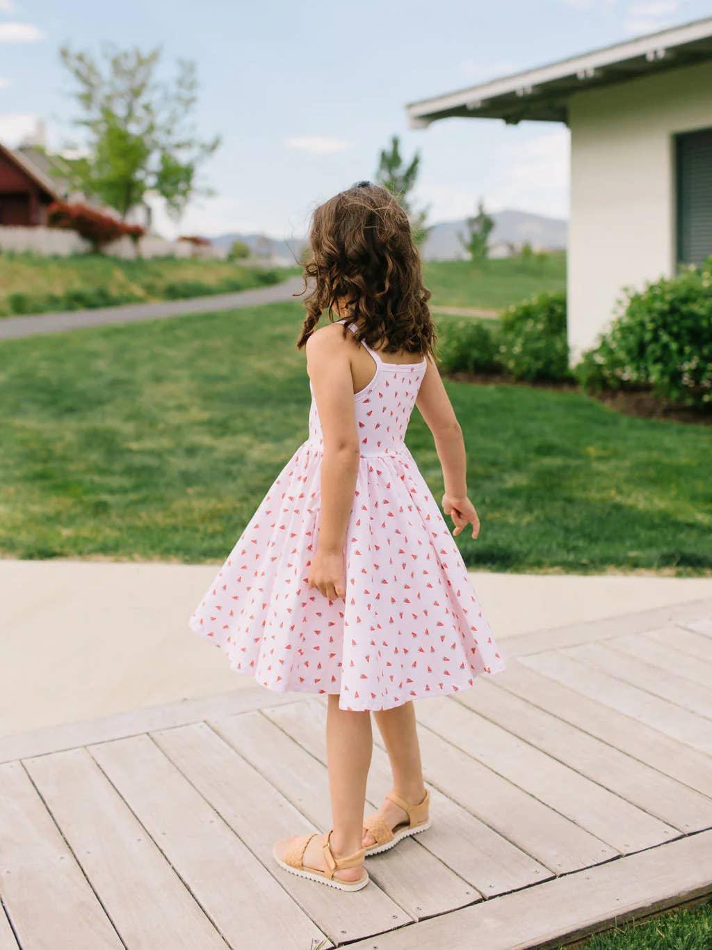 this picture shows the young girl wearing the sundress and slightly twirling showing movement in the full skirt. 