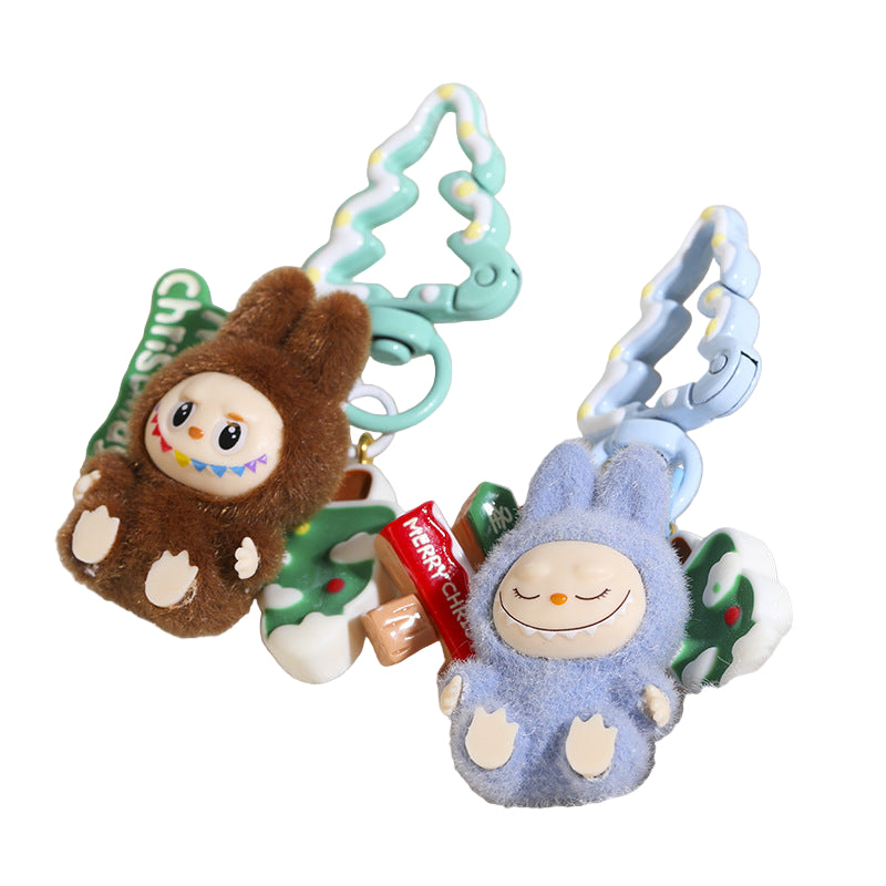 Two plush keychains, one brown and one blue, on a soft white surface.