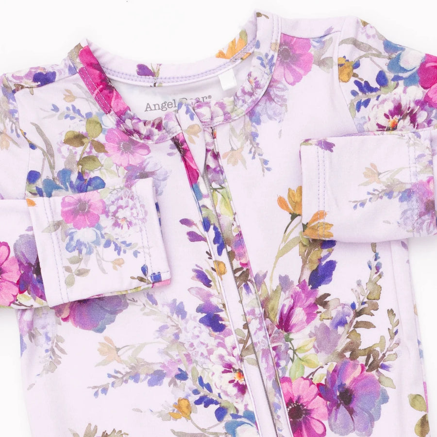 A close-up of a children's long-sleeve top or pajama with a light lavender base and a colorful watercolor floral print in pink, purple, blue, green, and yellow. The brand name 'Angel Dream' is visible on the inner neck label.