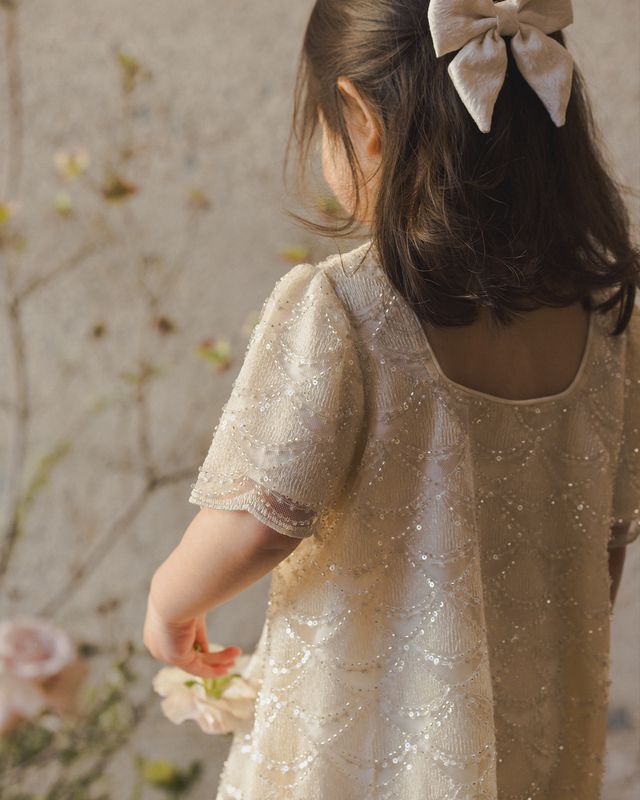 Child wearing a sparkly dress with a floral background