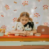 girl modeling with 2 of the stuffed dogs: one black and white and one all white.
