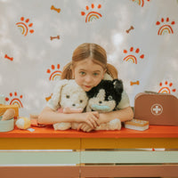 girl modeling with 2 of the stuffed dogs: one black and white and one all white.