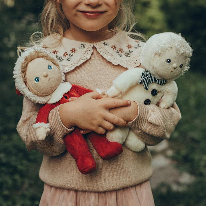 child holding 2 baby dolls dressed in Holiday attire