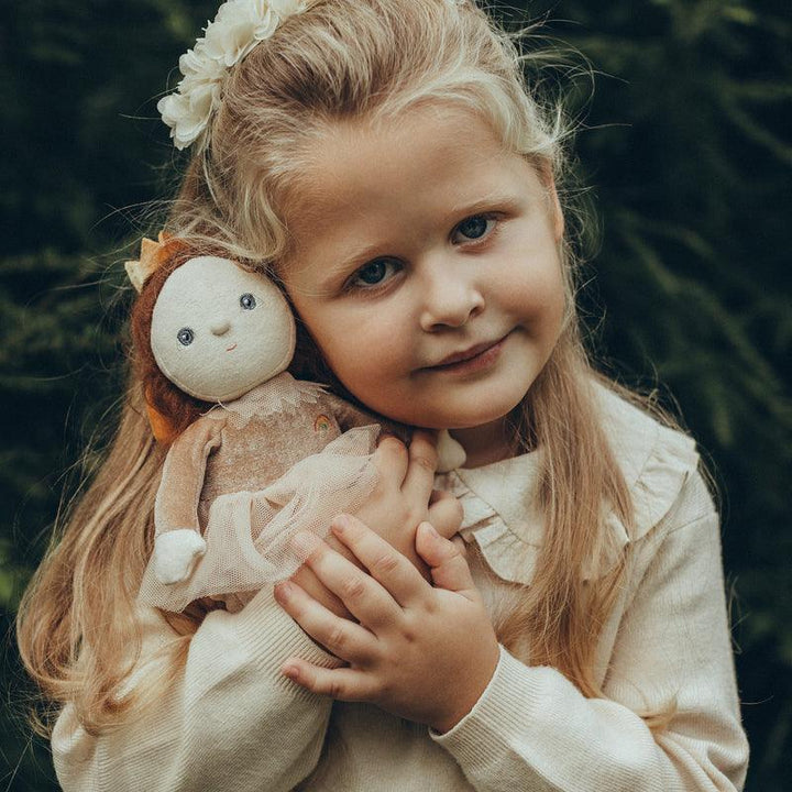 little girl snuggling the baby doll dressed as a sugar plum fairy