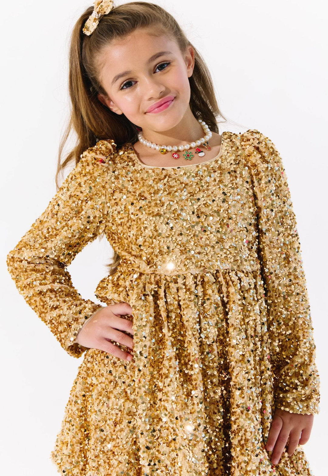 Young girl wearing a gold sequin dress on a white background
