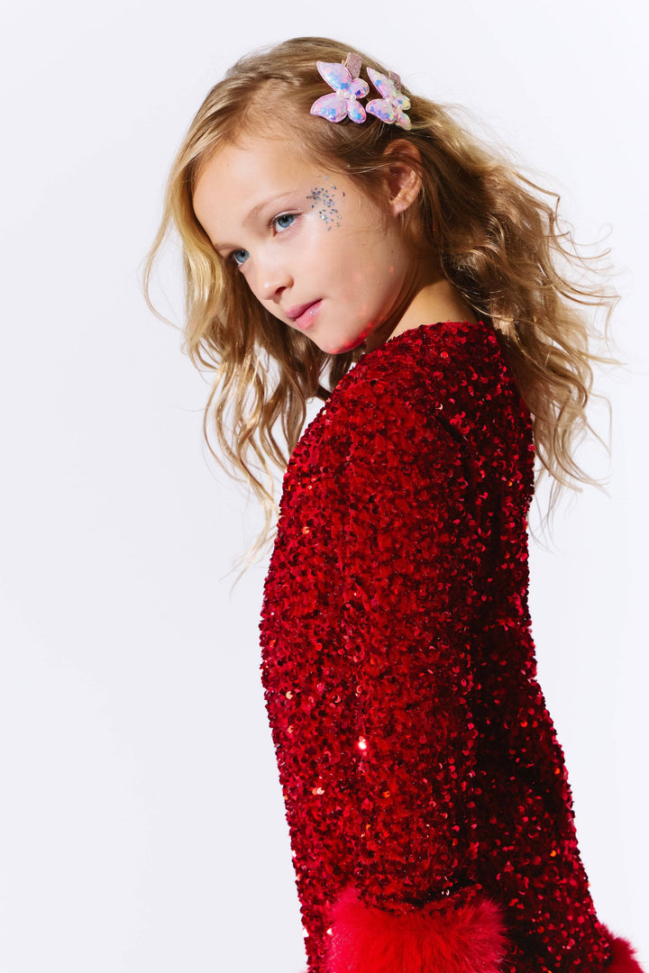 Young girl wearing a red sequin dress against a white background