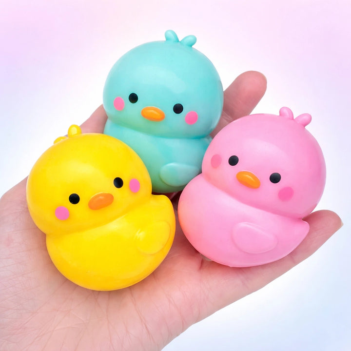 Three colorful duck-shaped squishies held in a hand against a white background