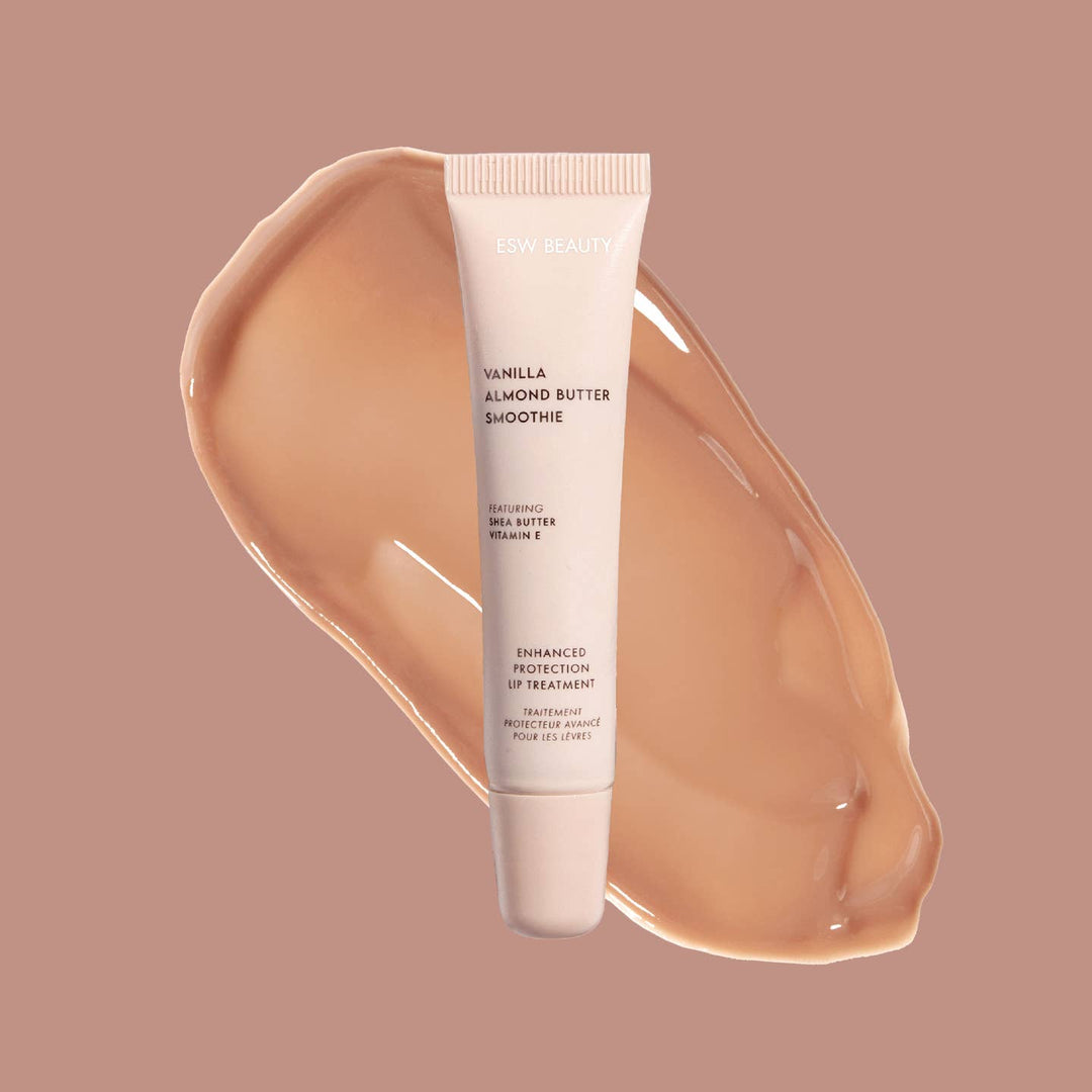 Tube of 'Vanilla Almond Butter Smoothie' lip treatment with a swatch of the product on a beige background