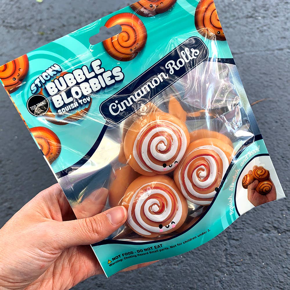 Packaged cinnamon rolls toy with 'Sticky Bubble Blobbies' branding on a dark surface.