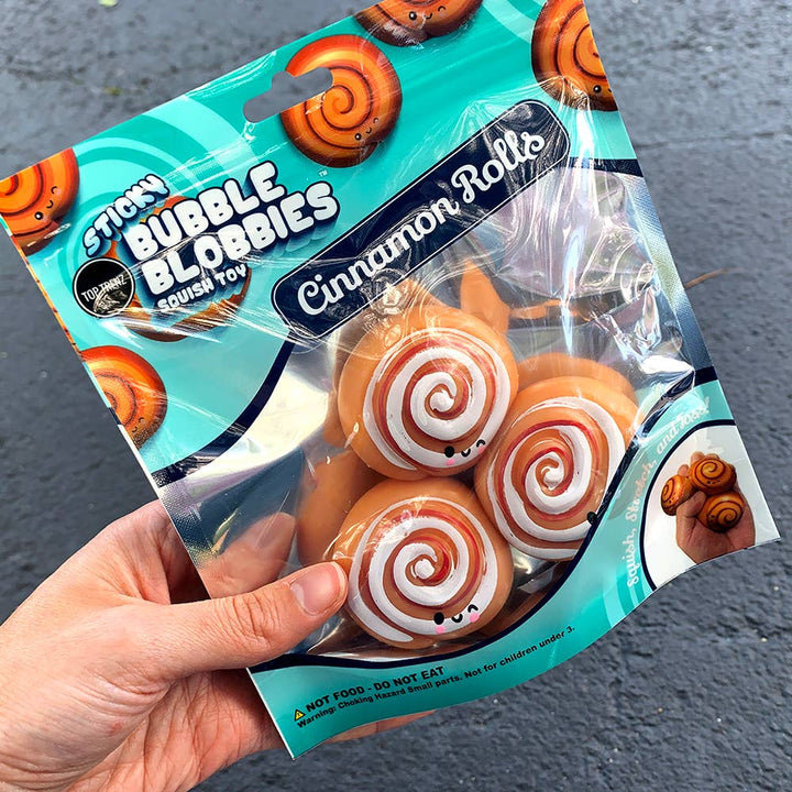 Packaged cinnamon rolls toy with 'Sticky Bubble Blobbies' branding on a dark surface.