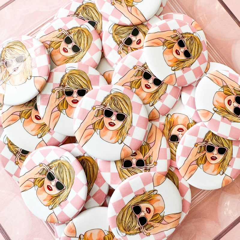 pic of Taylor swift from her 1989 Era on a pinback button. Behind Taylor is a pink and white check background