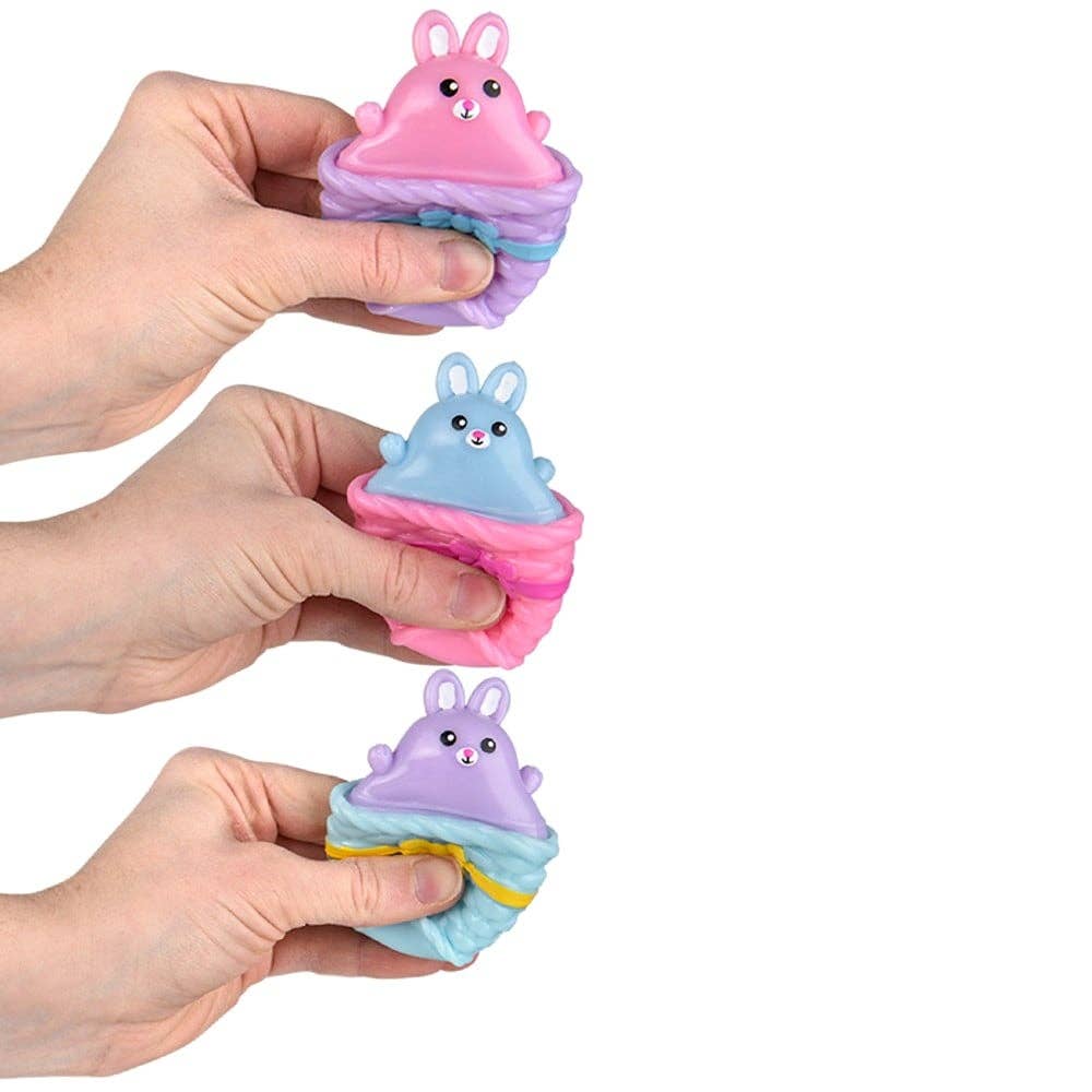 Hands holding colorful squishy toys shaped like cupcakes with animal faces on a white background