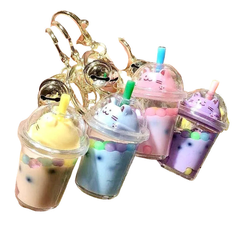 Colorful keychains shaped like bubble tea cups with straws held by a hand.