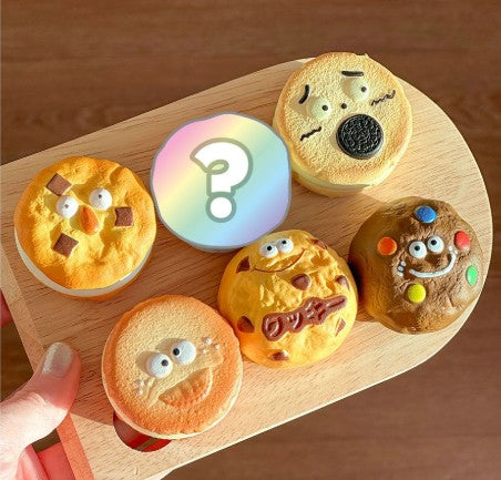 Five cartoon-style cookie keychains with facial expressions on a wooden board.