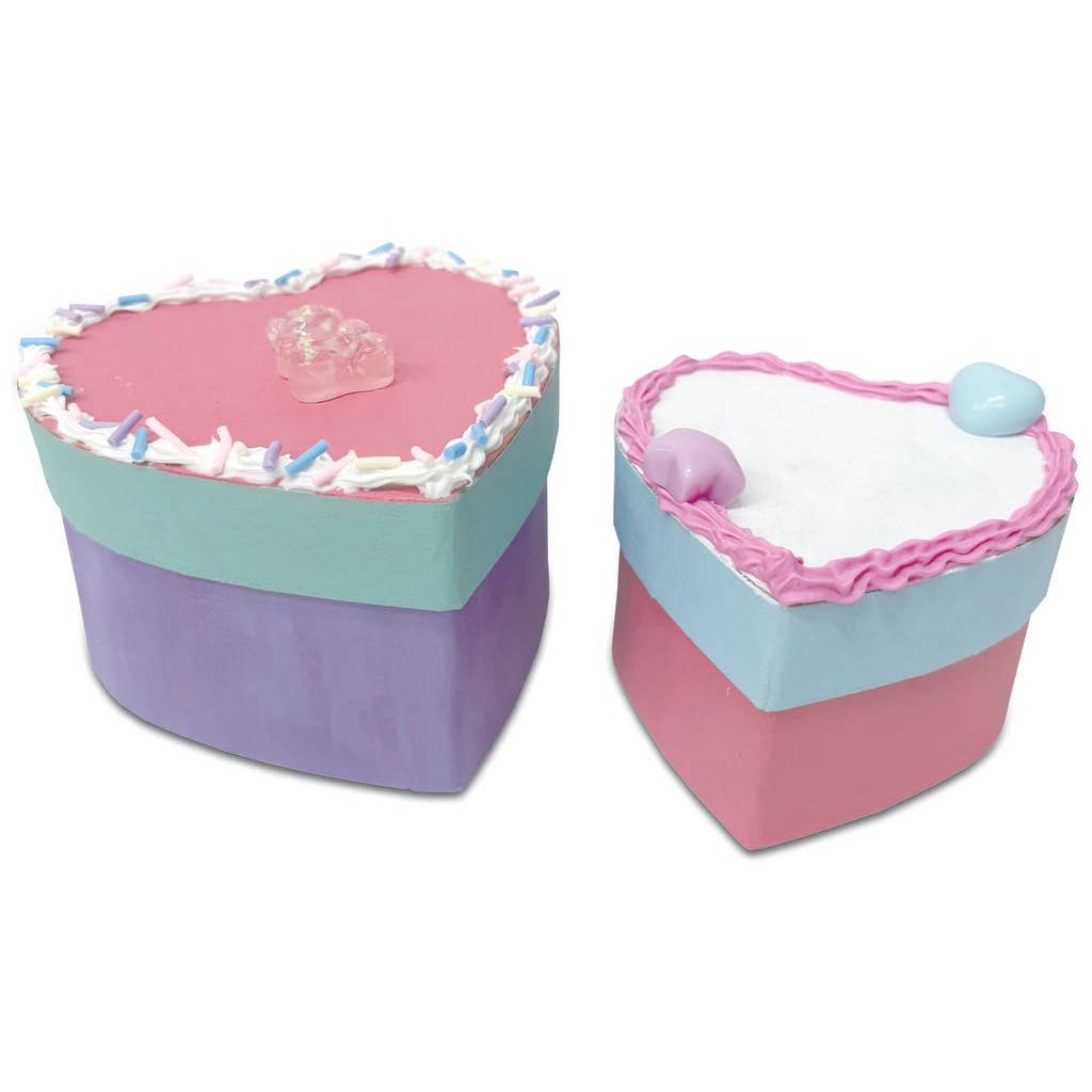 Two heart-shaped boxes with colorful icing and decorations on a white background