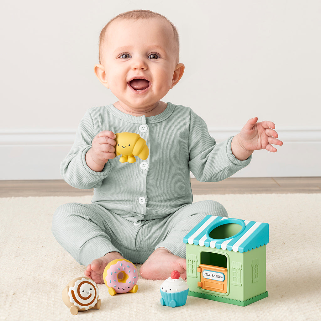 Baby playing with colorful toys on a light wooden floor.
