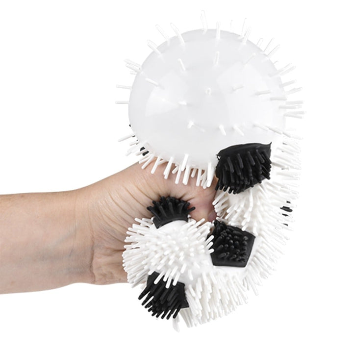 Hand holding a white and black textured ball with spikes