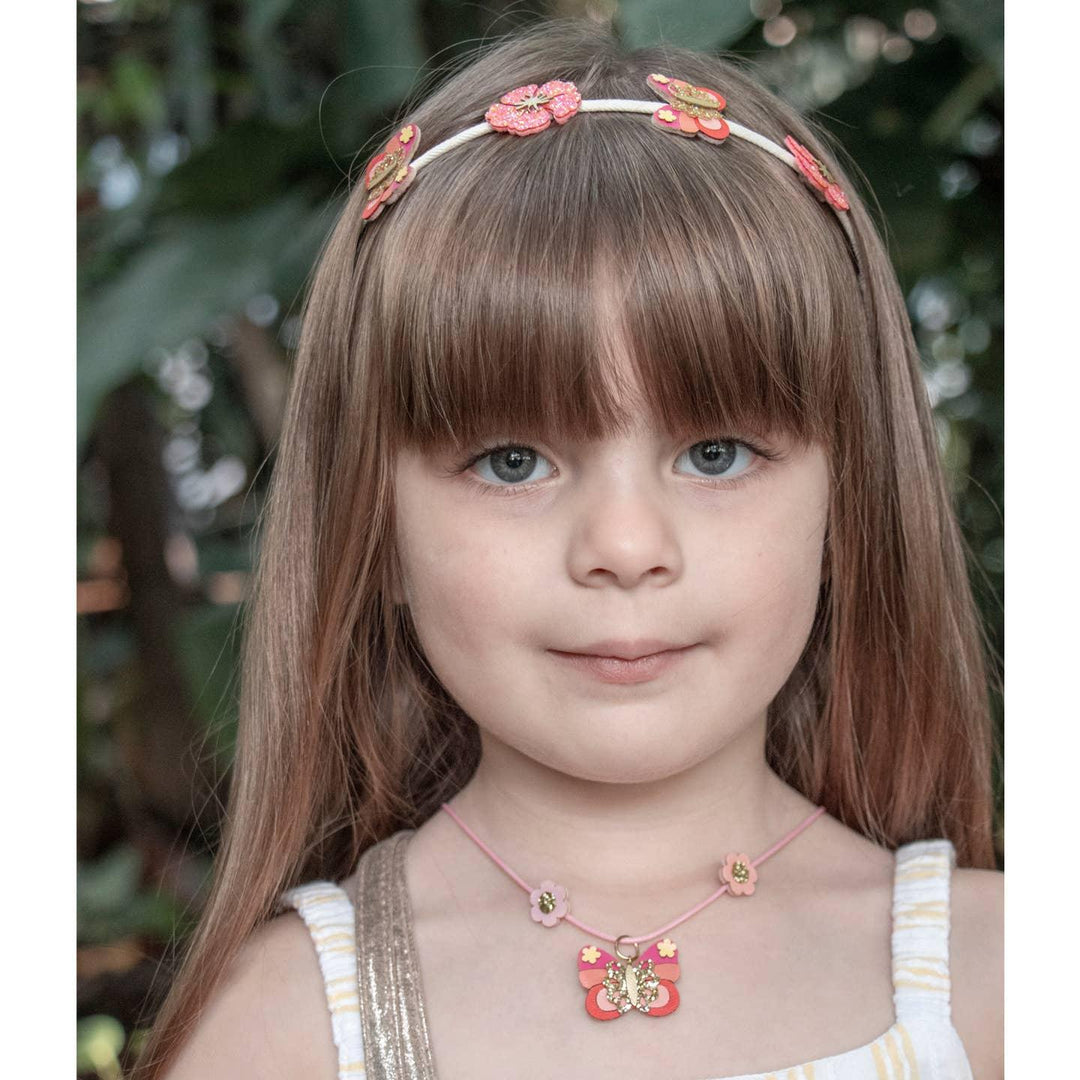 little girl wearing the bella butterfly headband in shimmering corals, hibiscus and butterflies. 