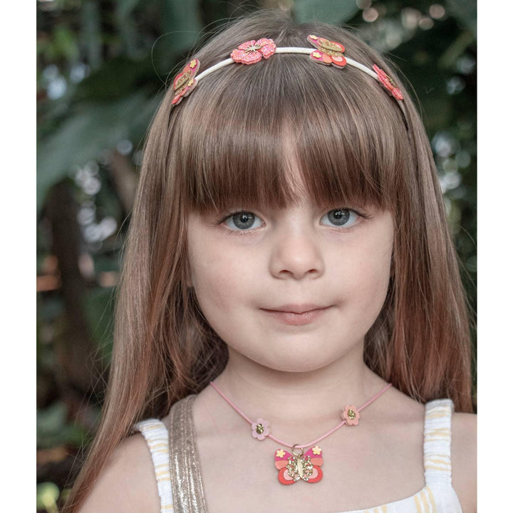 little girl wearing the bella butterfly headband in shimmering corals, hibiscus and butterflies. 
