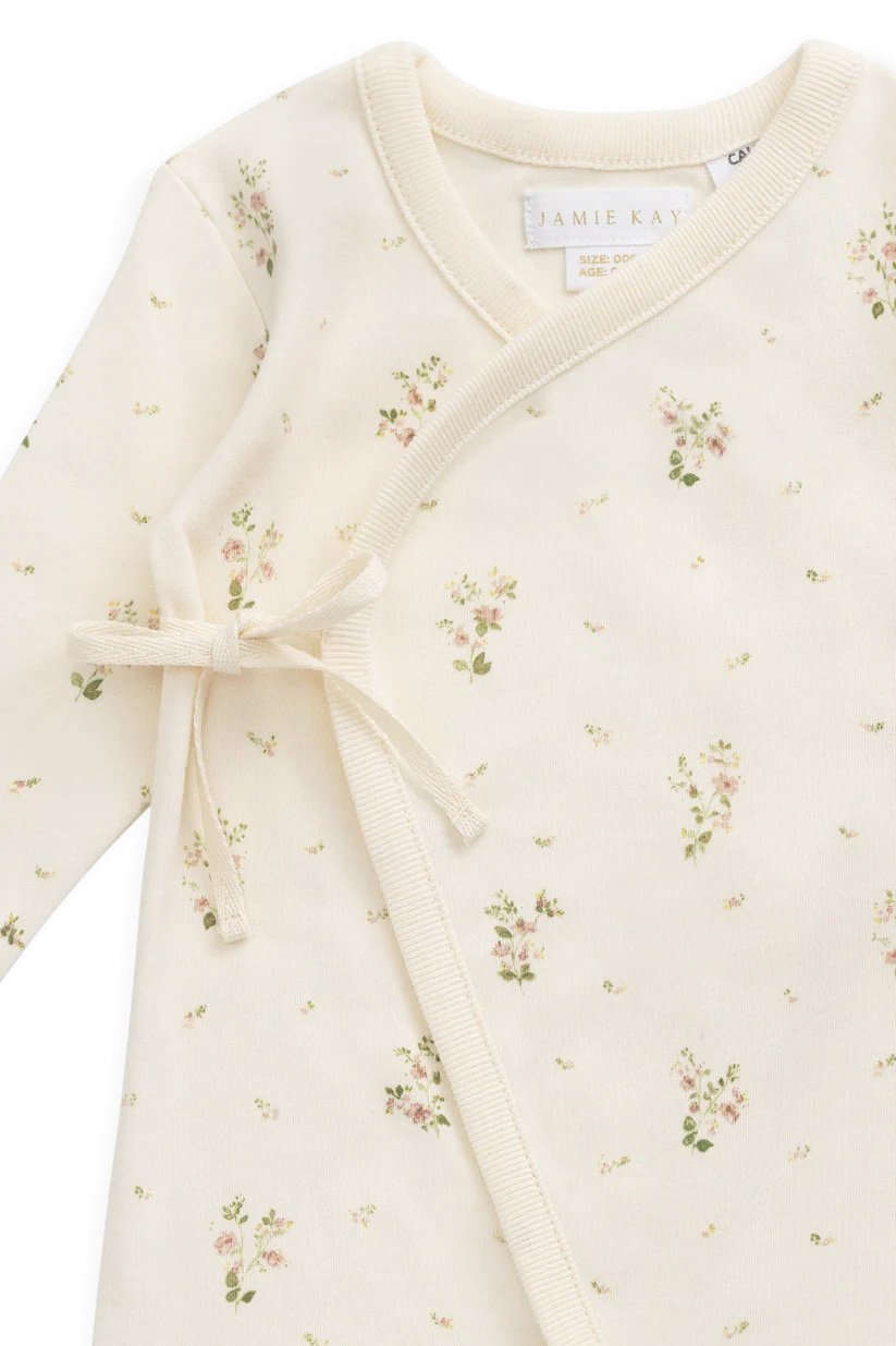 Floral patterned baby romper with a bow on a white background