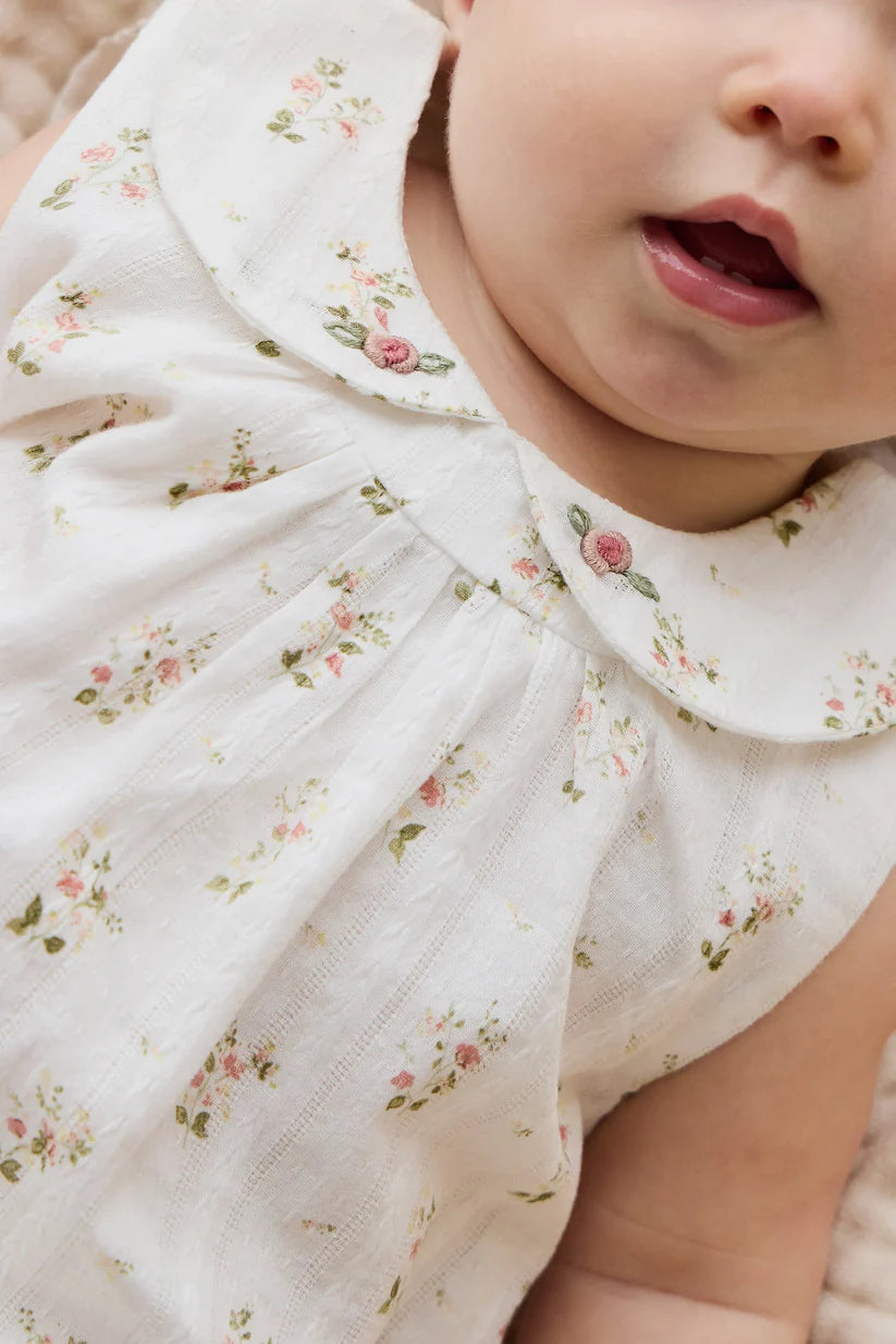 Close-up of a baby wearing a white floral dress.