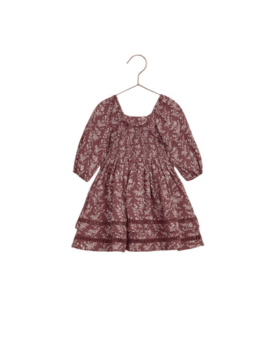 girls dress in a wine color, 3/4 sleeves with a peasant style. Light beige color vines and floral pattern all over the dress. 