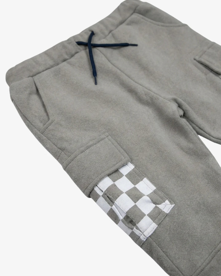 Close-up of gray fleece pants with a navy drawstring and a white-and-gray checkered pocket detail on the lower leg, shown on a light gray background.