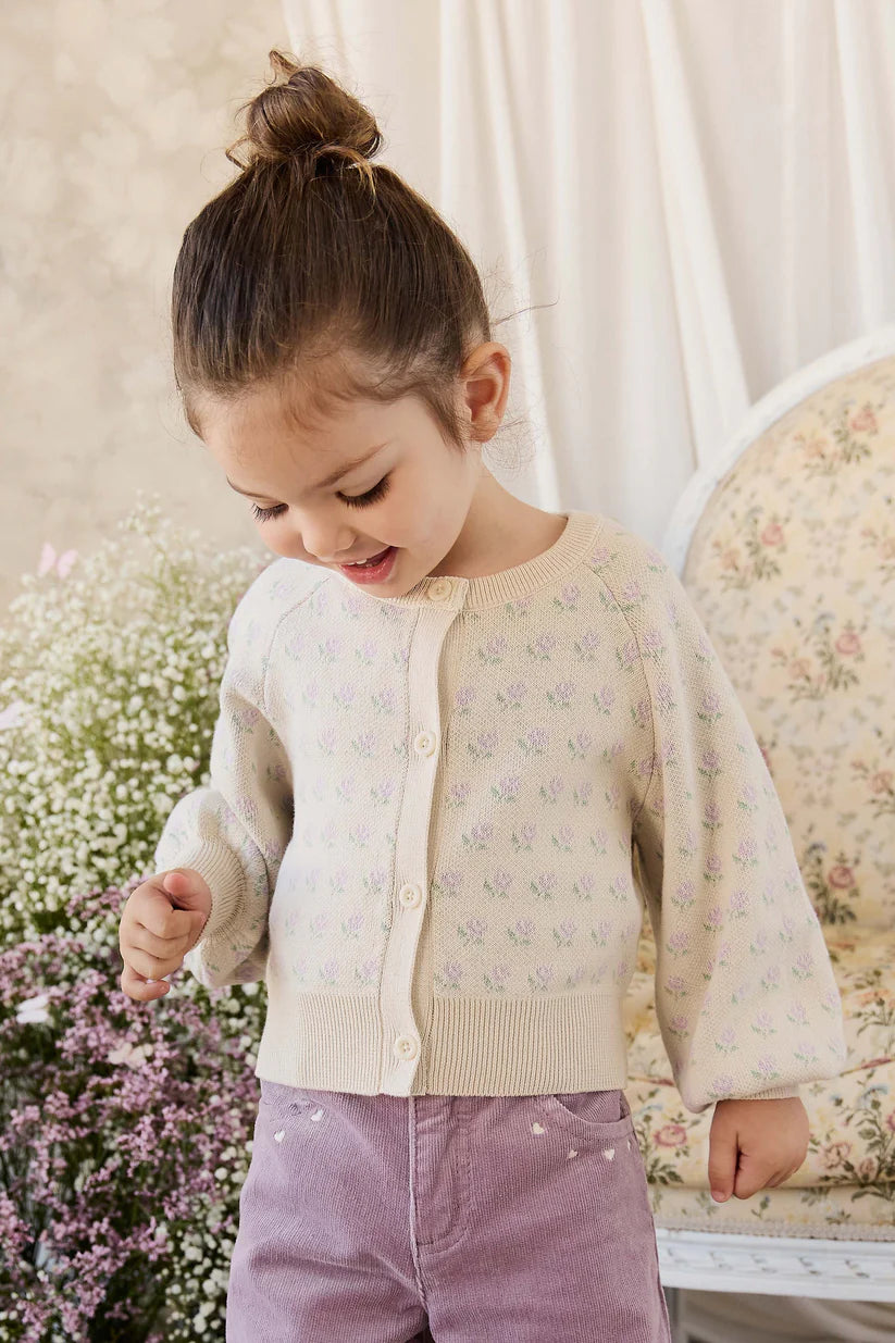Child wearing a floral patterned cardigan in a soft, indoor setting