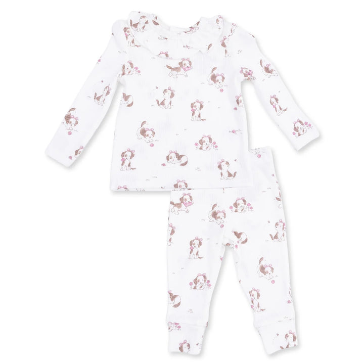 A two-piece baby pajama set featuring a long-sleeve top and matching pants in white, decorated with a repeating pattern of brown and pink cartoon dogs.