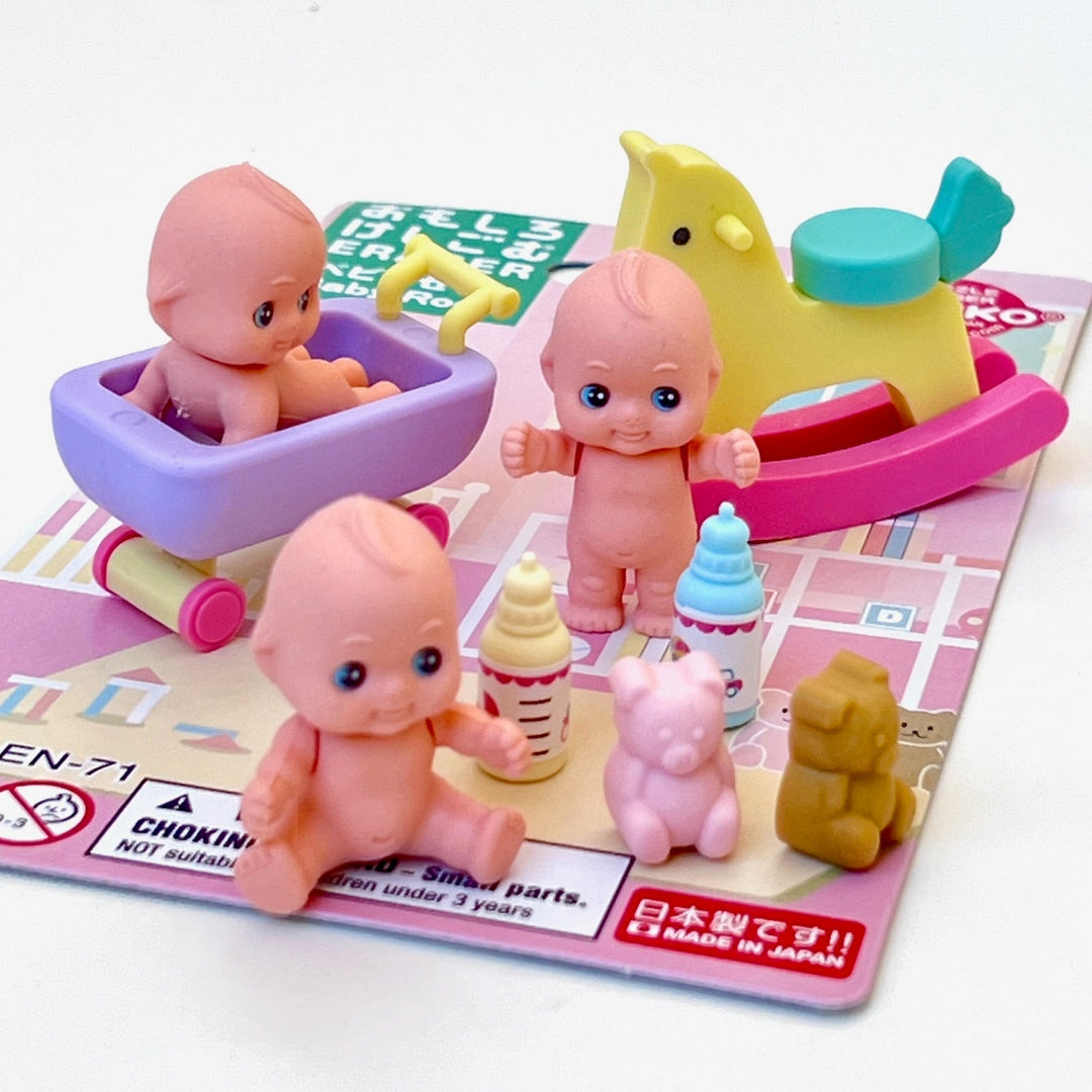 Toy figures of a baby and animals on a play mat with toys around. Items are actually erasers 