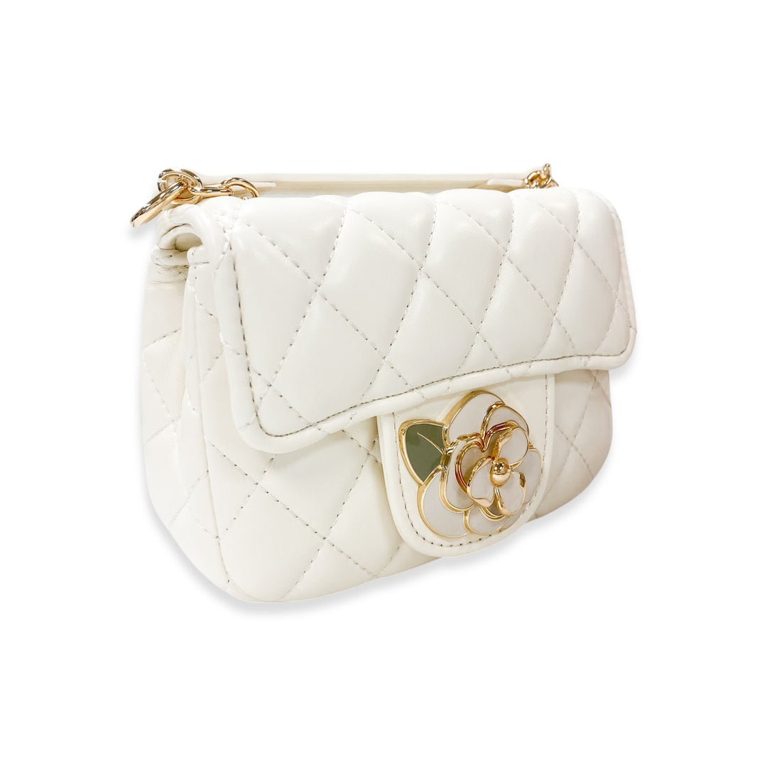 White quilted handbag with a decorative flower charm on a white background