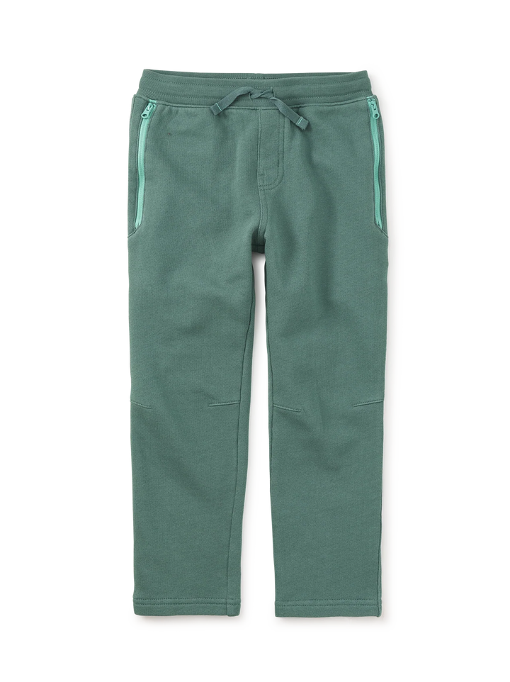 A pair of sage green fleece pants with a drawstring waist and zippered side pockets, shown flat on a white background.