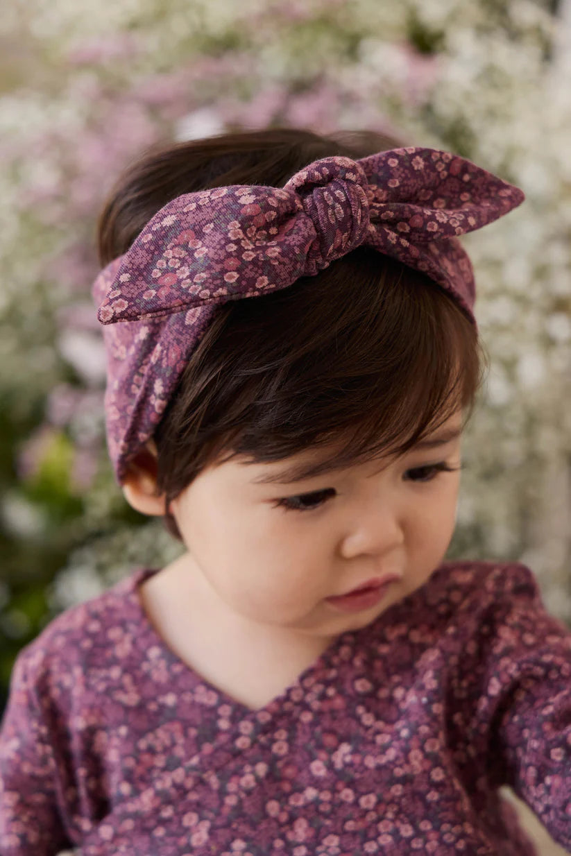 Child wearing a floral headband and outfit with a blurred floral background