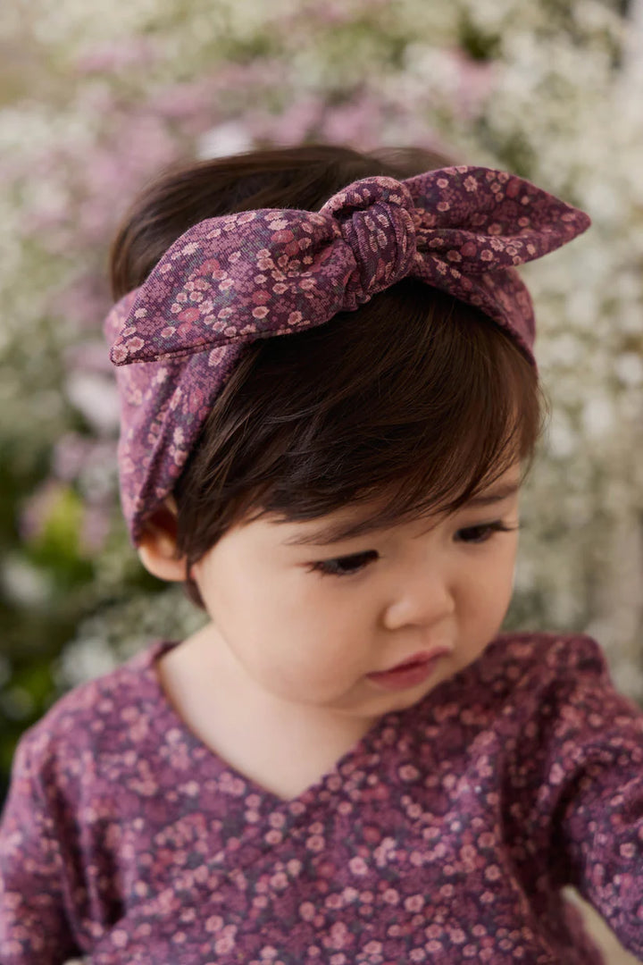 Child wearing a floral headband and outfit with a blurred floral background
