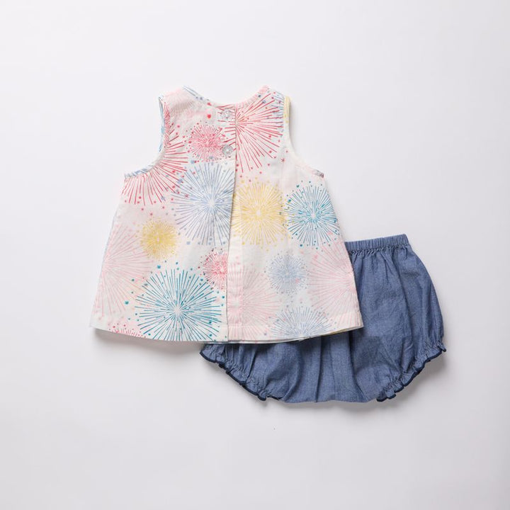 Children's outfit with a patterned top and blue shorts on a white background
