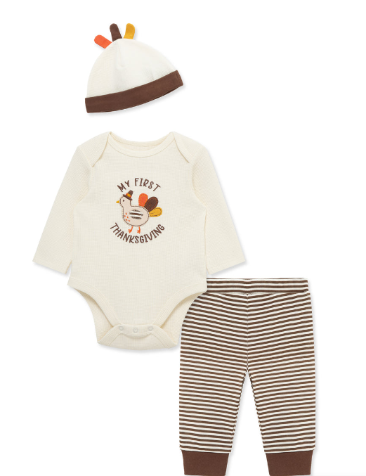 A baby Thanksgiving outfit set featuring a cream long-sleeve bodysuit with a turkey graphic and the text 'MY FIRST THANKSGIVING', brown and cream striped pants with brown cuffs, and a matching cream hat with brown trim and small turkey feather accents, all on a white background.