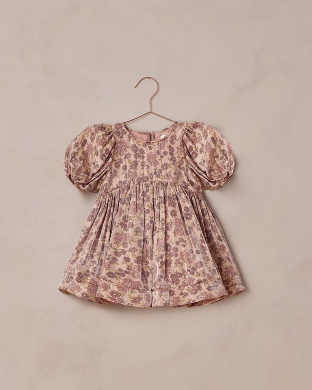 Floral dress with puff sleeves on a beige hanger against a beige background