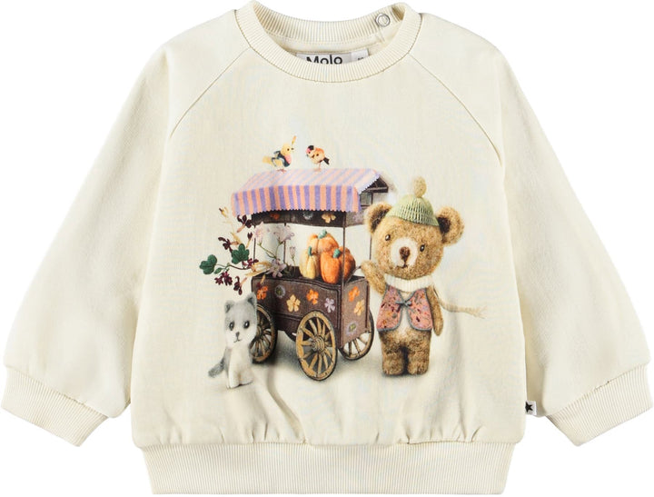 An off-white long-sleeve sweatshirt featuring a colorful graphic print of a teddy bear, a small cat, and a market cart with pumpkins. The brand name 'Molo' is visible on the inner neck label.