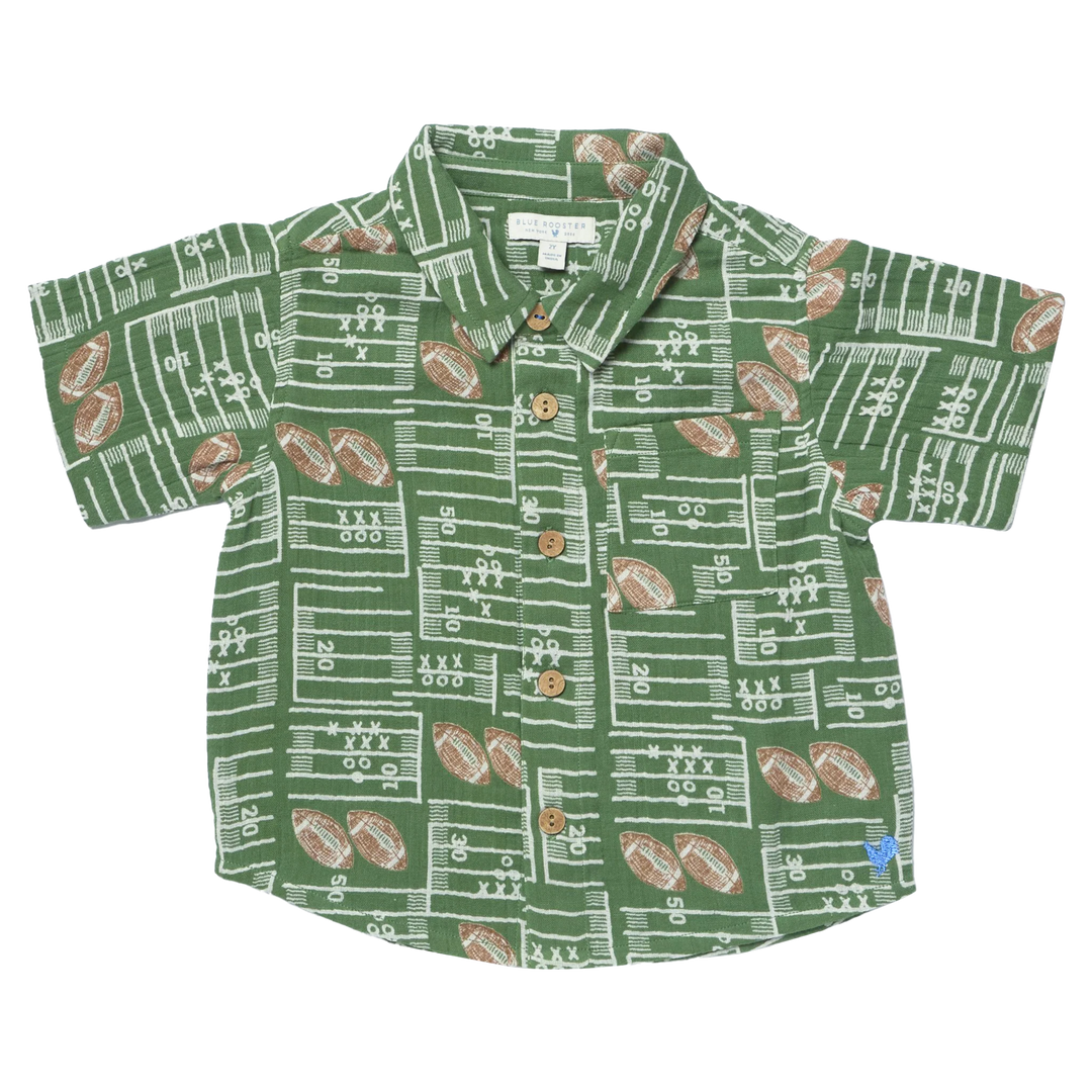 A short-sleeve button-up shirt for kids, featuring an all-over football field and football pattern in green, white, and brown, laid flat against a white background.