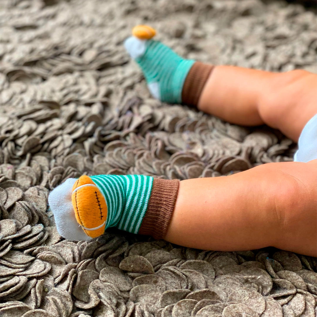 baby wearing the striped socks with footballs attached to the toes. 