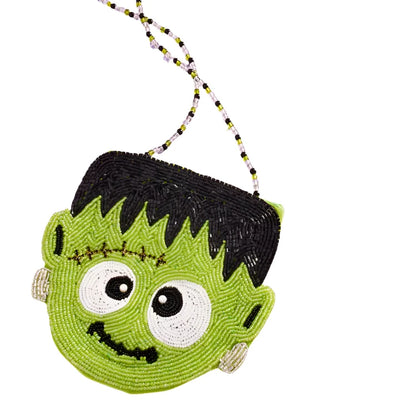 close up of Frankenstein's face and silly expression. Crossbody bag in the shape of Frankenstein. he is a green face and black hair. 