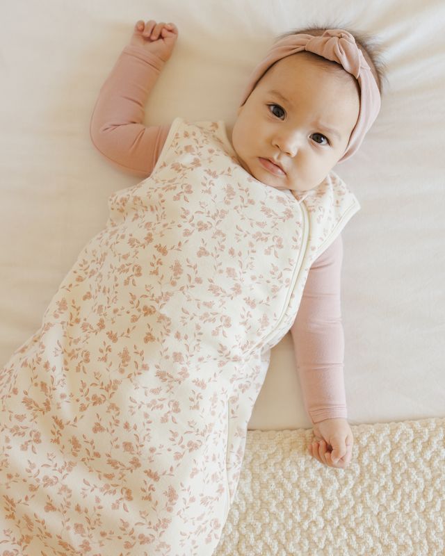 Baby wrapped in a floral swaddle blanket with a pink headband 