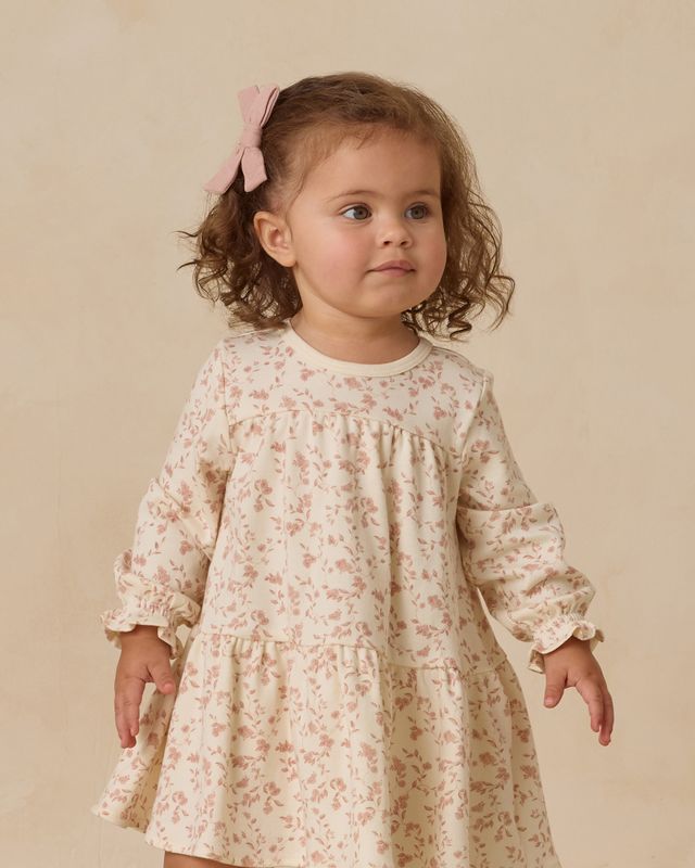 Young child wearing a pink floral dress against a beige background