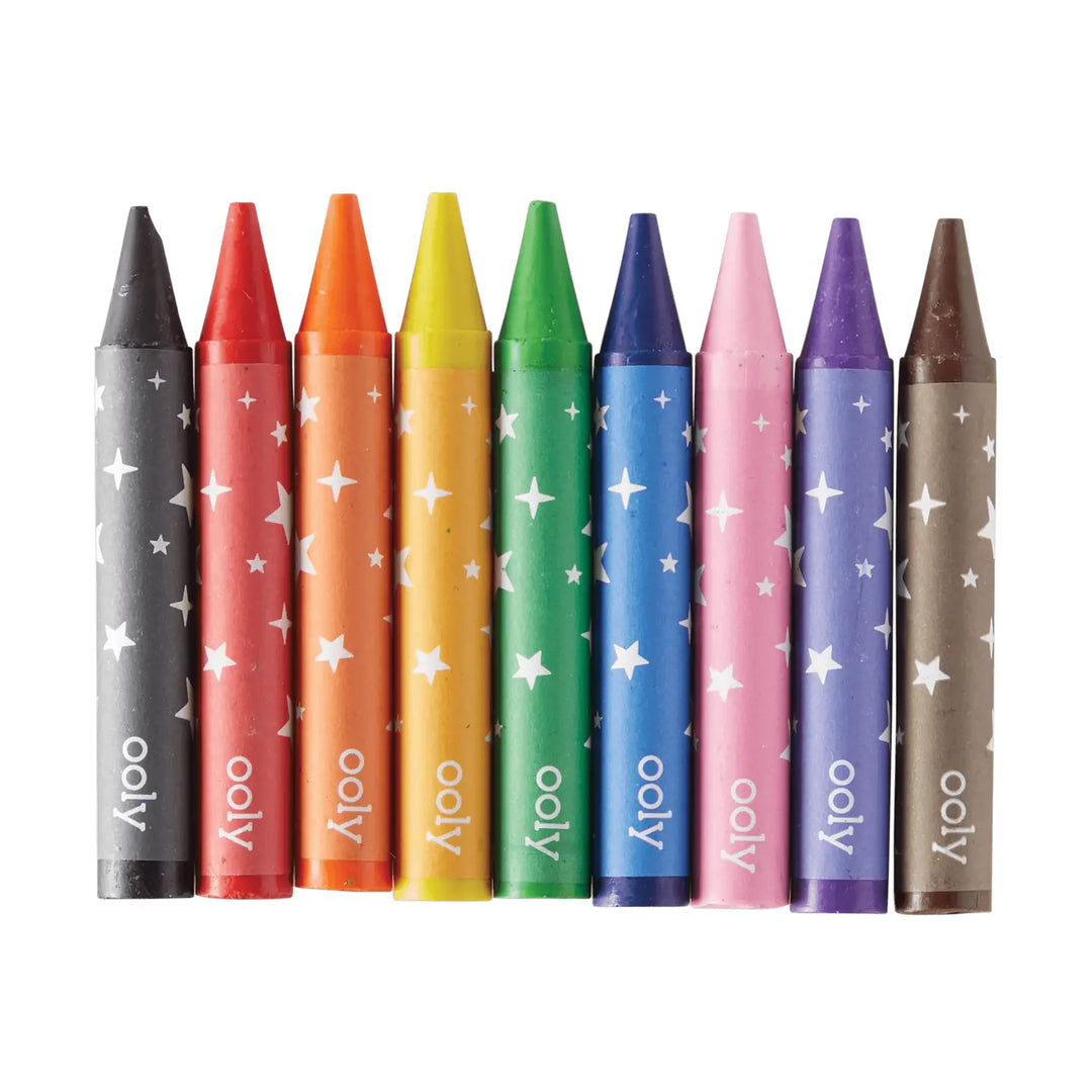 Eight Oily crayons in a row, showing a range of colors from dark gray to brown, each decorated with a white star and moon pattern.