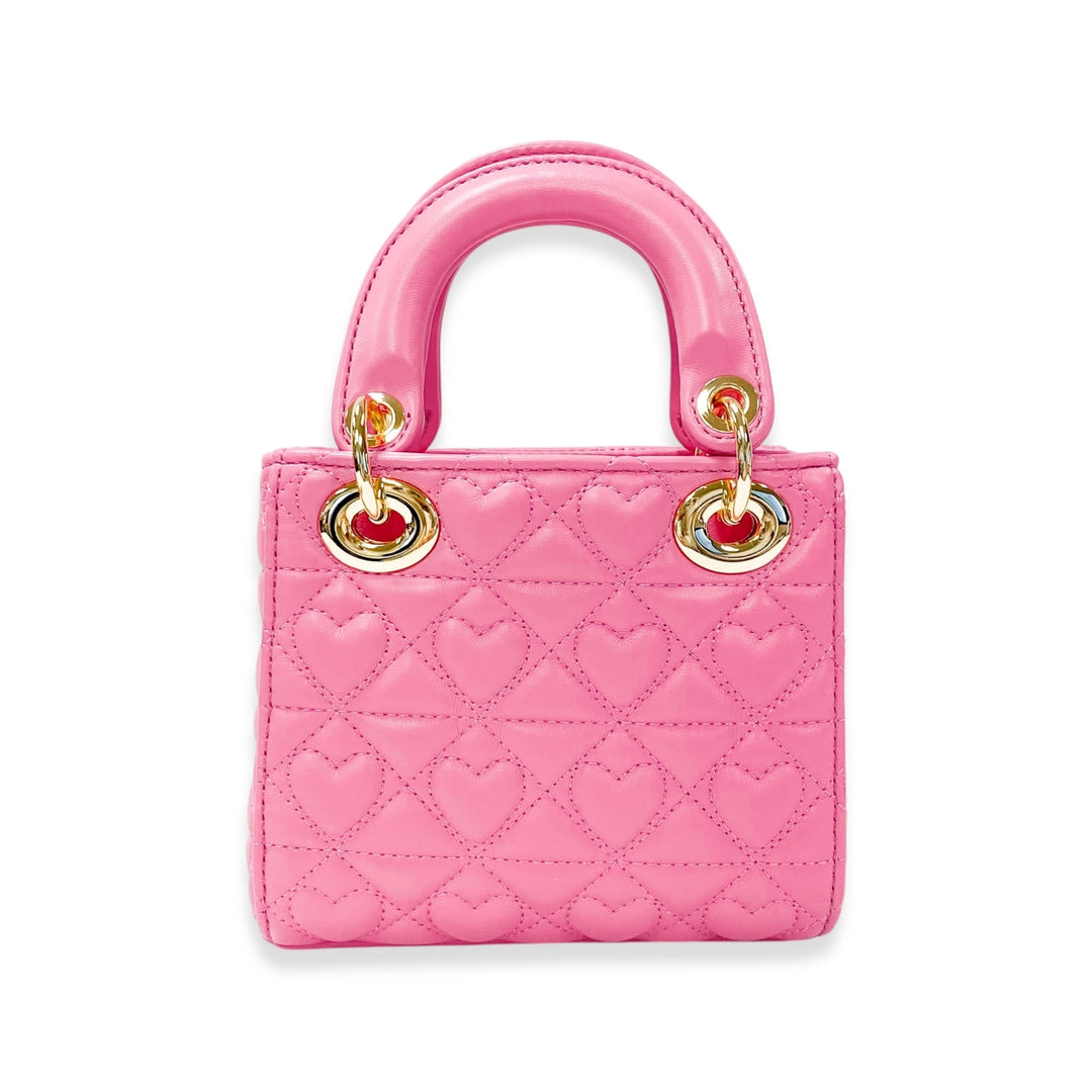 Pink quilted handbag with heart patterns on a white background