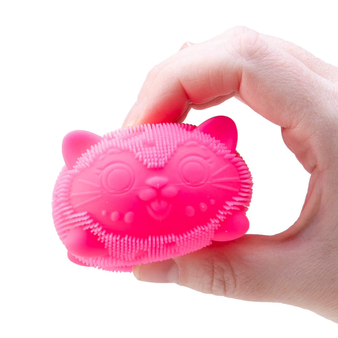 Pink cat-shaped scrubber held in a hand against a white background