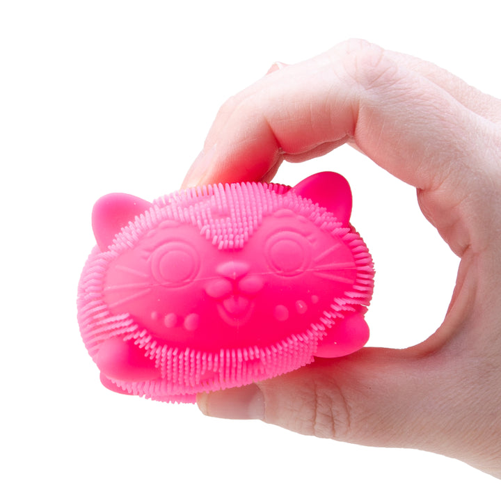Pink cat-shaped scrubber held in a hand against a white background