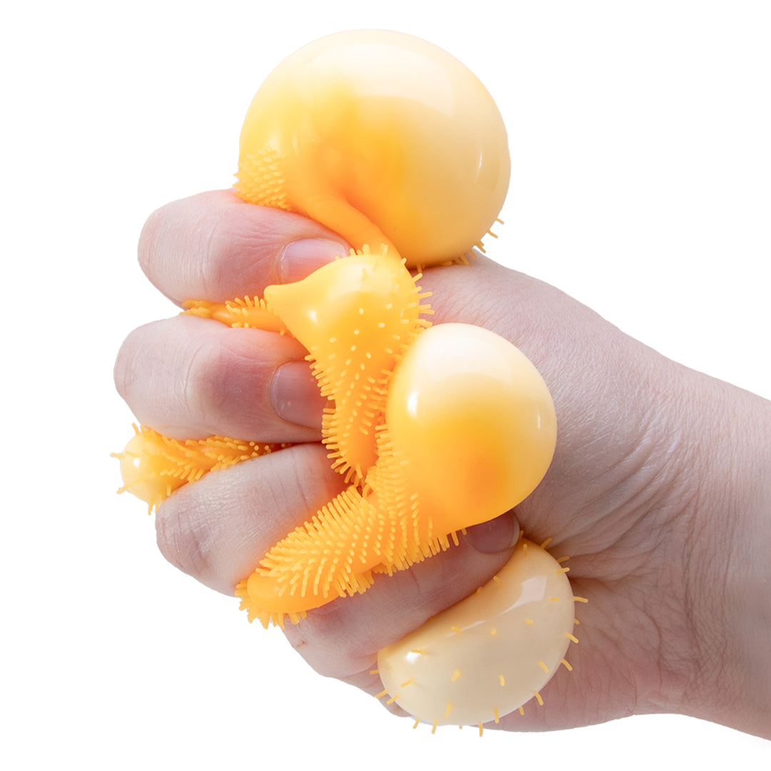 Hand holding a yellow textured ball against a white background