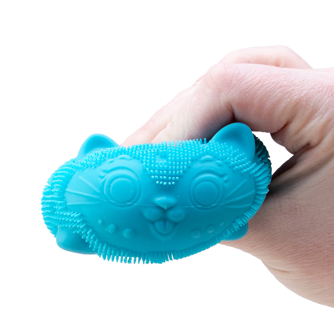 Blue silicone brush held in a hand against a white background